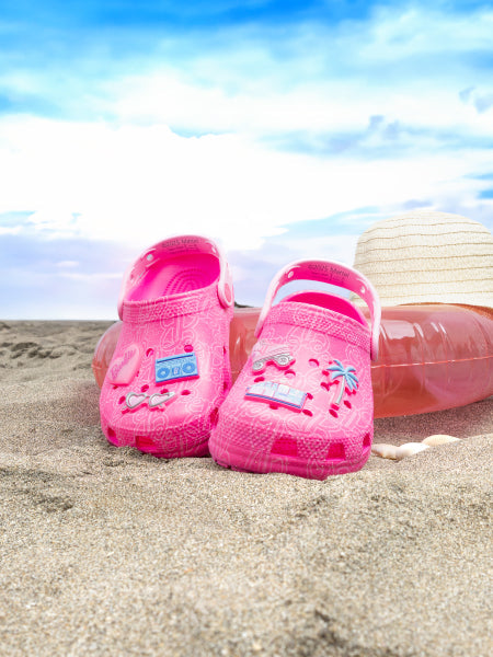 Zoom in a pies de niña utilizando sandalias color nude con pantalon rosa sobre fondo lila.